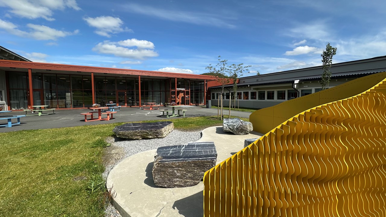 Bilde av skolen inngangsareal tatt på en sommerdag.