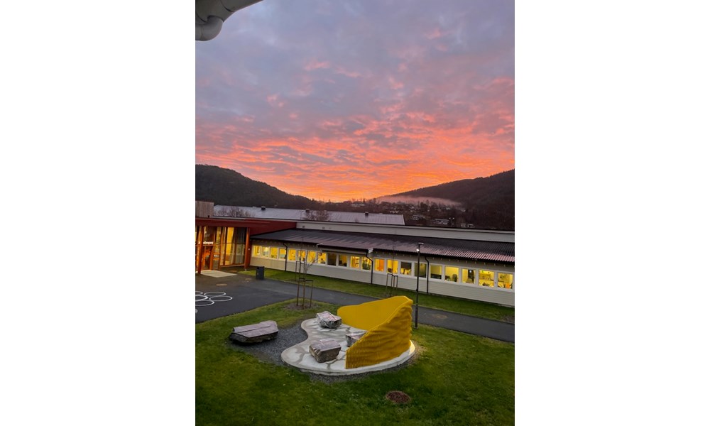 Bilde av skolen med rosa himmel i bakgrunnen. Foto: Mette Bårdli