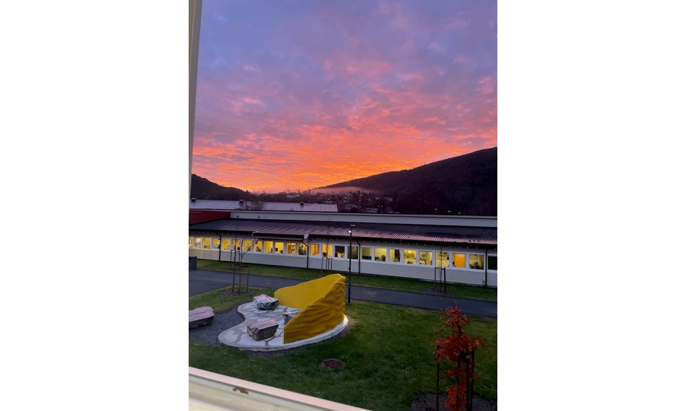 Bilde av skolen med rosa himmel i bakgrunnen. Foto: Mette Bårdli