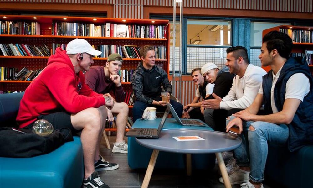 sosialt biblioteket.jpg Ei gruppe elevar sit rundt eit bord i biblioteket.