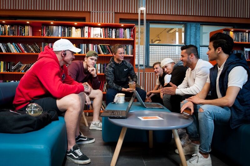 Ei gruppe elevar sit rundt eit bord i biblioteket.