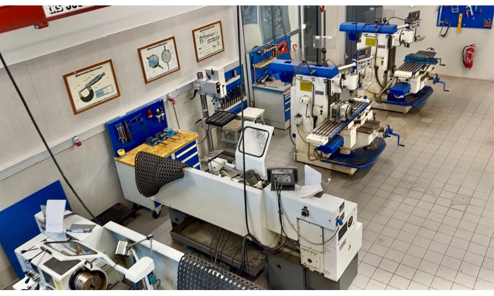 Bildet viser et profesjonelt verksted med tunge maskiner sett fra et fugleperspektiv.