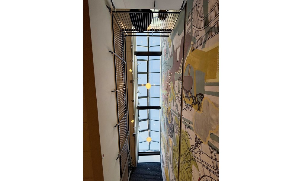 Bildet viser et stort glasstak i en mørk stålkonstruksjon slipper inn mye naturlig dagslys