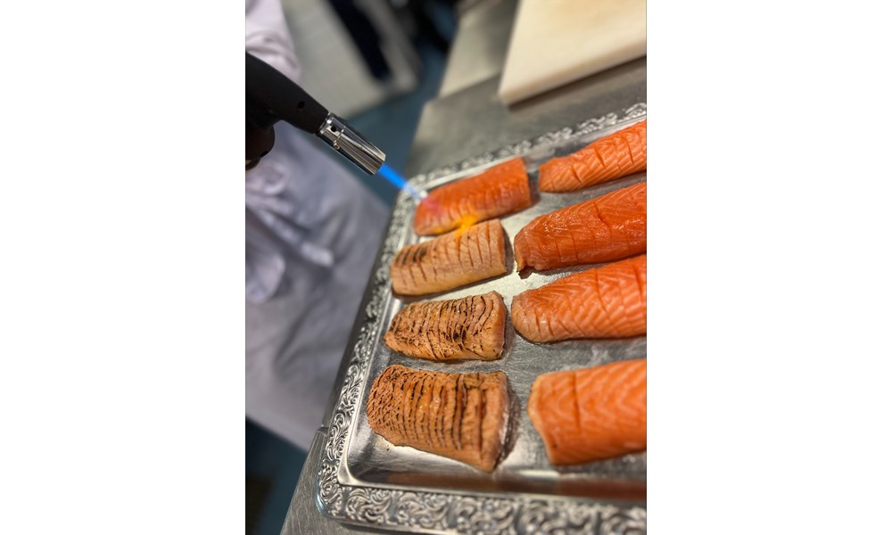 Dette bildet viser en teknikk der overflaten på laksefileter blir lett brent med en gassbrenner.