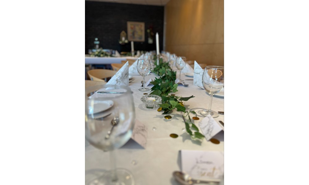 Dette bildet viser et langbord som er profesjonelt dekket for et selskap eller en markering.
