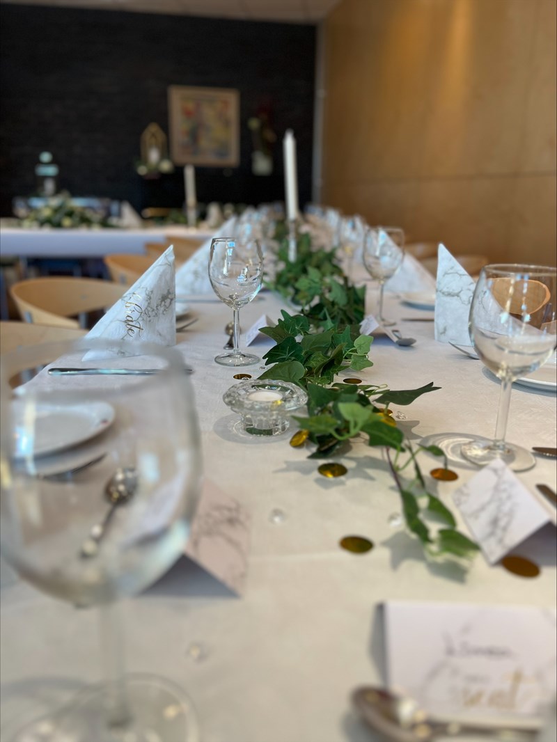 Dette bildet viser et langbord som er profesjonelt dekket for et selskap eller en markering.
