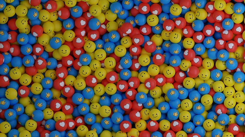 Illustrasjonsbilde som viser masse små kuler i rødt, gult og blått med ulike emojitegn på.