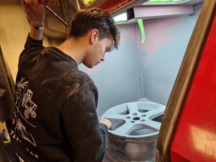 Gutt arbeider på en felg som ligger inne i et avtrekk